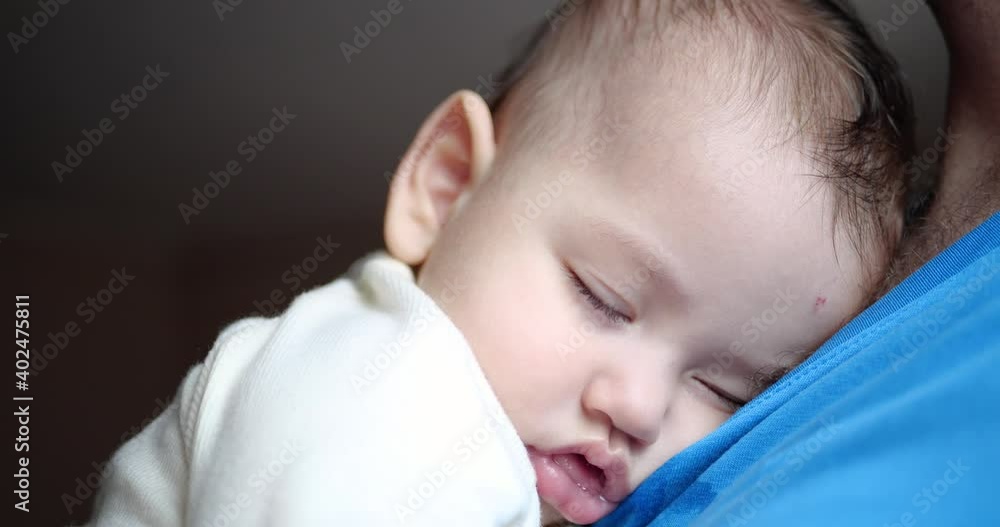 a small child fell asleep in his father's arms. dad rocking the baby to sleep. close-up . 4k a small child fell asleep in his father's arms. dad rocking the baby to sleep. close-up . 4k