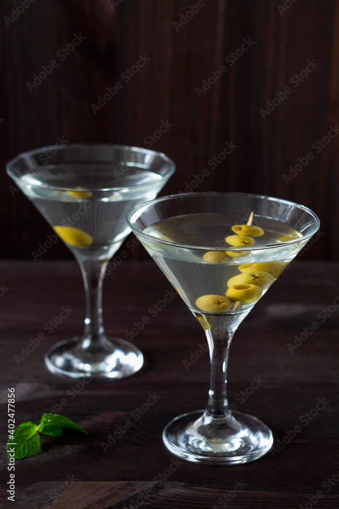 Two glasses margarita cocktail in the bar. martini glasses of cocktail with olives on wooden background. Glasses for martini and green mint on the black table. copy space. alcohol drinks.