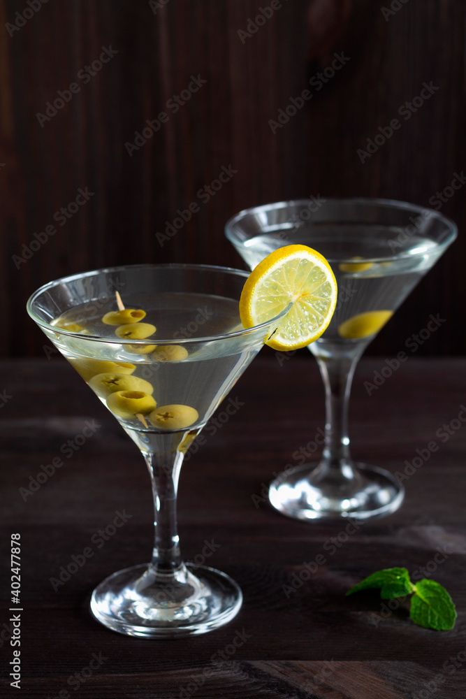 Two glasses margarita cocktail in the bar. martini glasses of cocktail with olives on wooden background. Glasses for martini with lemon and green mint on the black table. copy space. alcohol drinks.