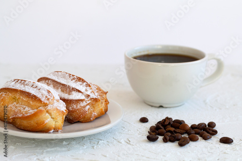 Plate with eclairs on a table. Coffee cup with coffee beans on white background. Traditional french tasty dessert.