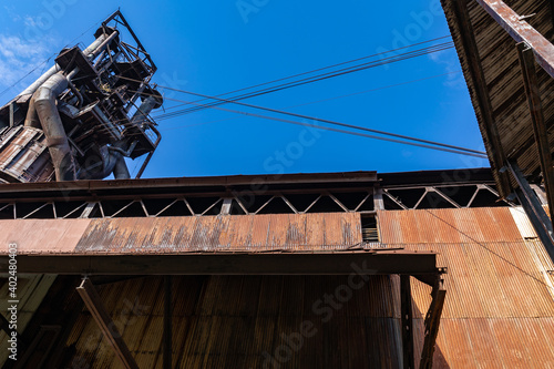 View looking up at derelict industrial structures, blue sky copy space, horizontal aspect