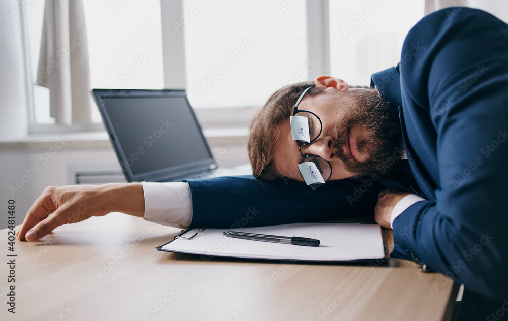 Business man in a suit fell asleep at work at the table in the office Business man in a suit fell asleep at work at the table in the office