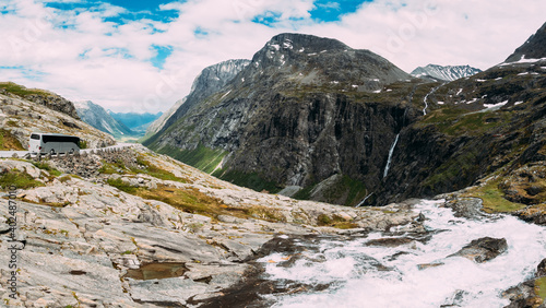 Trollstigen, Andalsnes, Norway. Bus Goes On Road Near Stigfossen Waterfall. Famous Mountain Road Trollstigen. Norwegian Landmark And Popular Destination. Norwegian County Road 63 In Sunny Summer Day photo