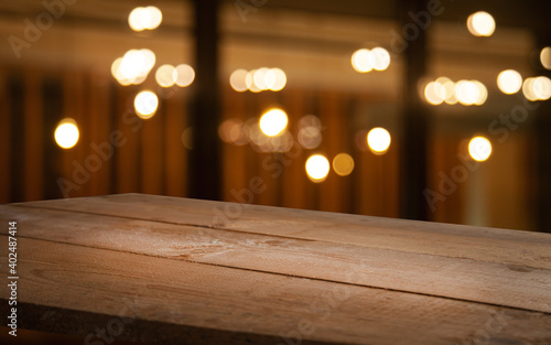 empty wooden table on blurred light gold bokeh of cafe restaurant on dark background  blurred cafe interior place for your products on the table