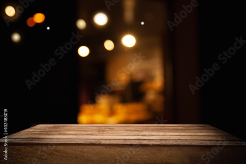 empty wooden table on blurred light gold bokeh of cafe restaurant on dark background  blurred cafe interior place for your products on the table