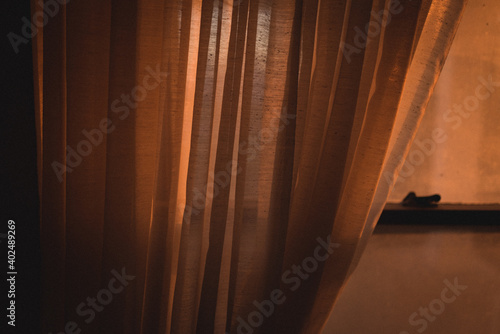 A window mostly covered by a curtain at sunset