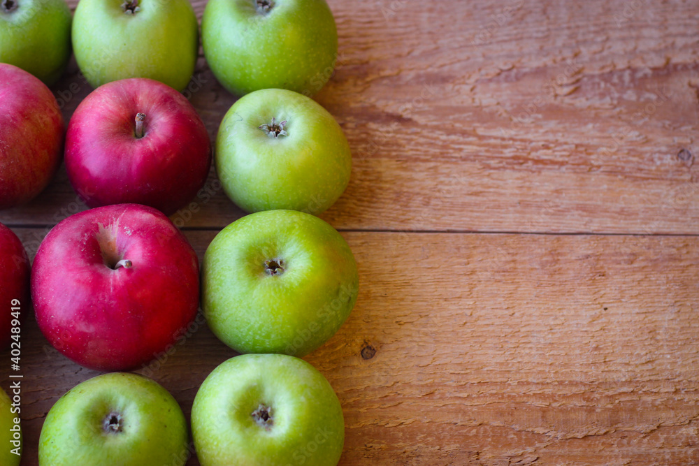 Green and red apples stand on a wooden surface Green and red apples stand on a wooden surface