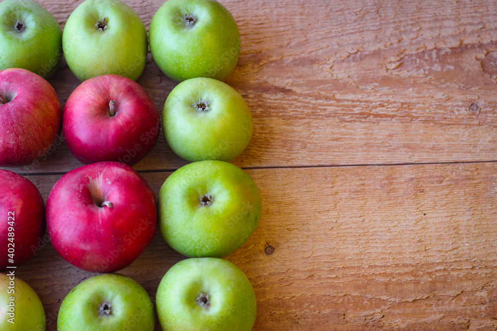 Green and red apples stand on a wooden surface Green and red apples stand on a wooden surface