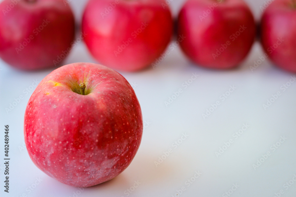 Red apples stand on a white surface