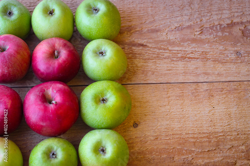 Green and red apples stand on a wooden surface