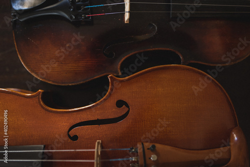Violin and viola sitting next to each other on dark background