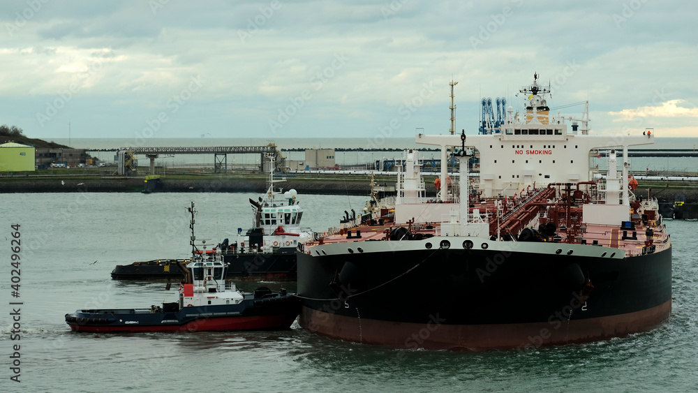 Obraz premium Two tugs assisting the ship to come alongside