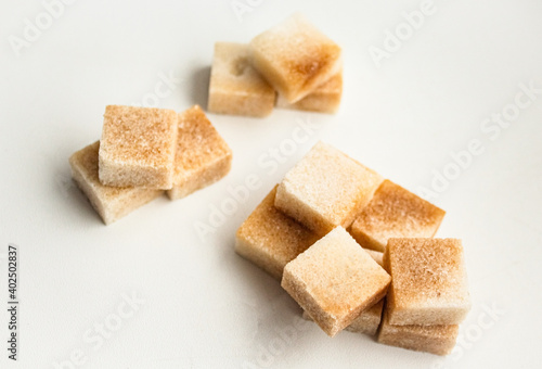 Reed sugar in the form of cubes lies on a white background with a handful