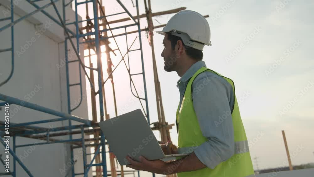 Engineer or inspector wearing white helmet and holding laptop to check and building control, Building exterior structure engineering on rooftop construction site Engineer or inspector wearing white helmet and holding laptop to check and building control, Building exterior structure engineering on rooftop construction site
