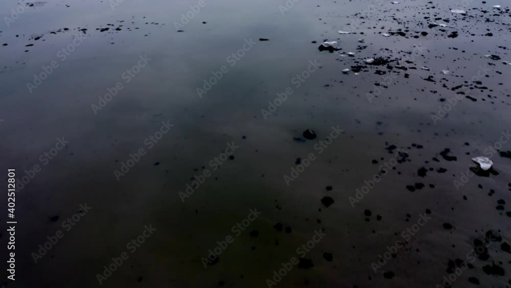 Drone flying over a calm river and revealing the vast Saint-Lawrence river in winter