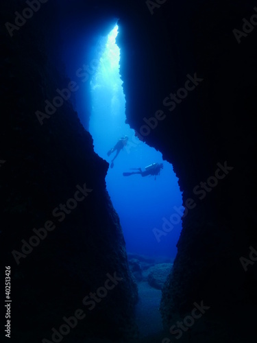 cave diving underwater scuba divers exploring caves and having fun ocean scenery sun beams and rays background © underocean