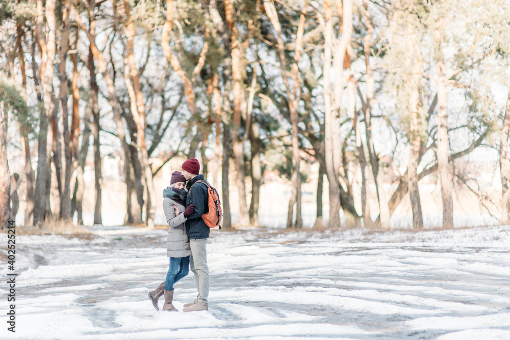 Young hipster couple hugging each other in winter park. Winter love story, a beautiful stylish young couple.