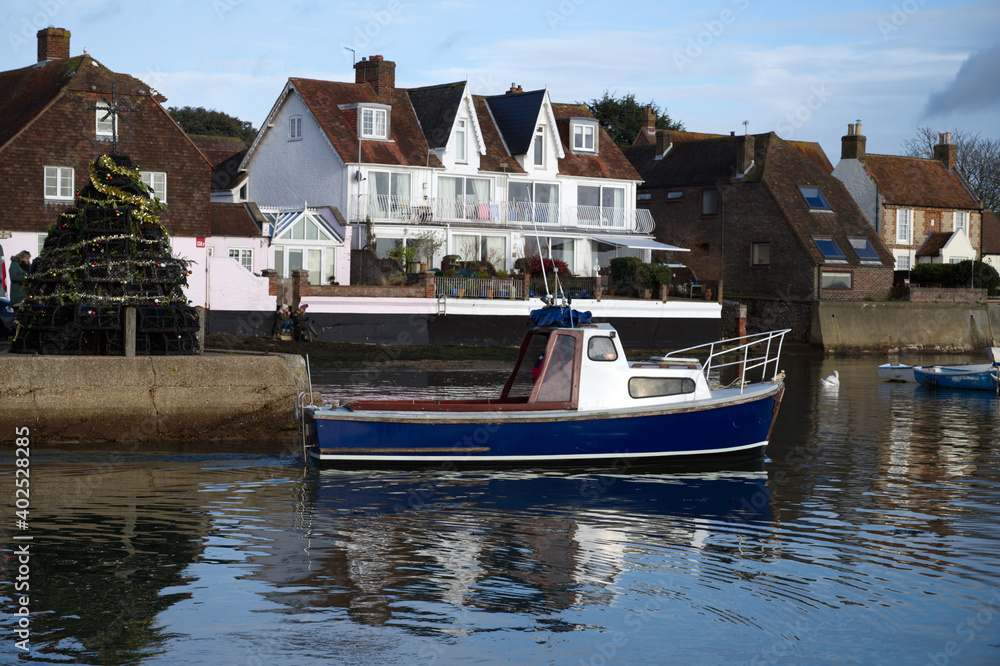 View of a local fishing boat leaving Emsworth Harbour with the Christmas Tree made of Lobster Pots in the background.