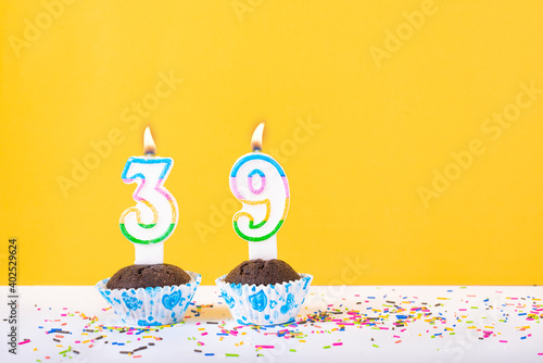 39 number candle on a cup cake with colorful sprinkles and yellow background thirty ninth birthday anniversary celebrations photo