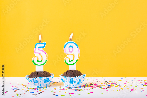 59 number candle on a cup cake with colorful sprinkles and yellow background fifty ninth birthday anniversary celebrations photo