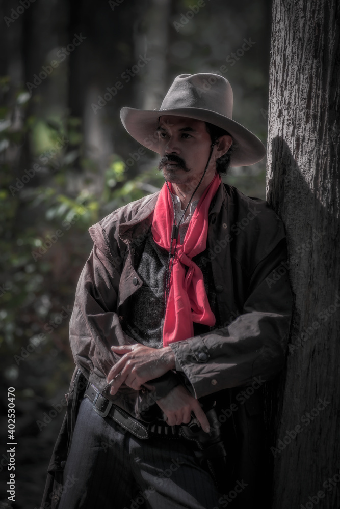 Cowboy is standing beside the tree. Cowboy costume concept. Western cowboy. Cowboy is standing beside the tree. Cowboy costume concept. Western cowboy.