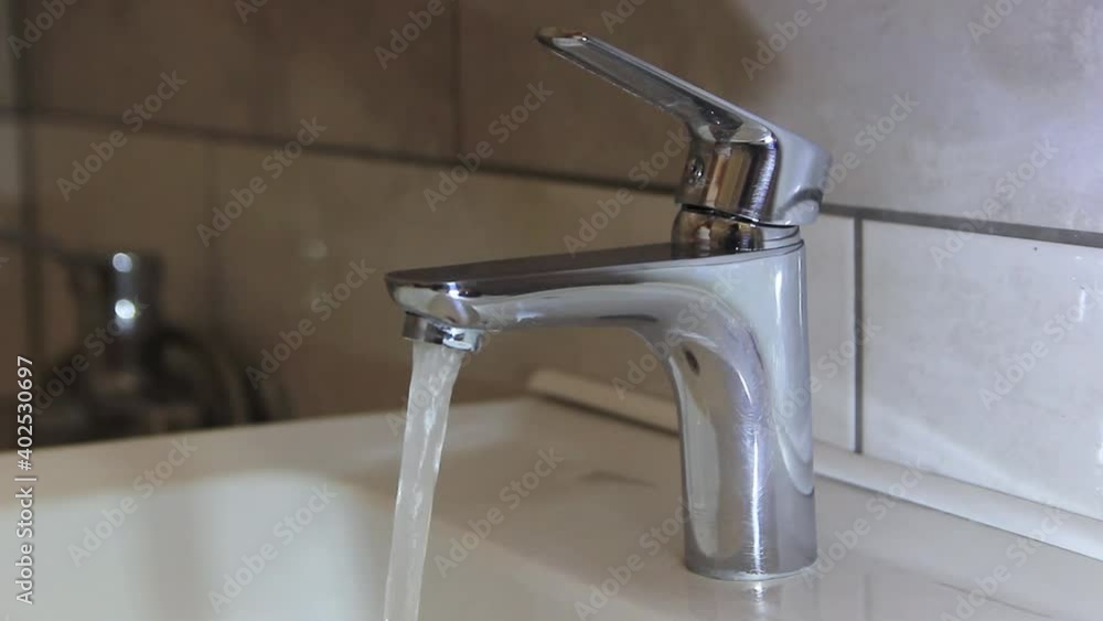 A woman's hand opens a tap with water. A woman's hand opens a tap with water.