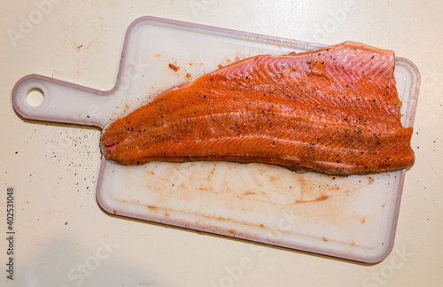 Fillet of salmon seasoned on a cutting board, top view