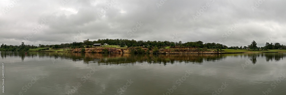 Beautiful panoramic view of river with reflections of small hills, trees and clouds on water, Hawkesbury river, Cattai national Park, New South Wales, Australia
