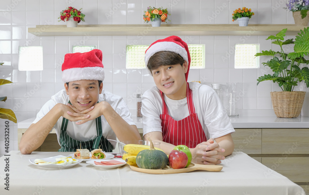 Young asian LGBT gay couple happy celebrating christmas and new year meal together in dining room on holiday. Selective focus. Young asian LGBT gay couple happy celebrating christmas and new year meal together in dining room on holiday. Selective focus.