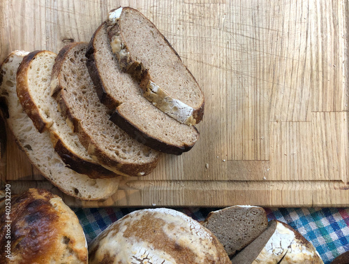 Slices of different sourdough breads on a wooden cutting board, rest of the breads on the bottom side