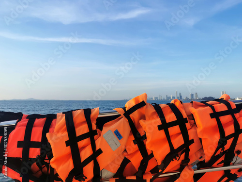 Orange life jacket important for life security in the water or the sea on blue sky background.