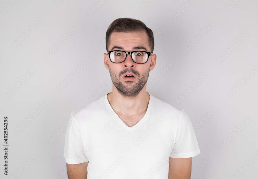 Surprised man in eyeglasses wearing white undershirt over grey background Surprised man in eyeglasses wearing white undershirt over grey background