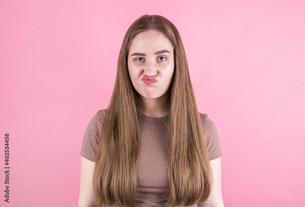 pretty brunette girl looks at the camera with a dubious and indecisive expression on her face, chasing her lips as if she is forbidden to say something. Confused young woman pretty brunette girl looks at the camera with a dubious and indecisive expression on her face, chasing her lips as if she is forbidden to say something. Confused young woman