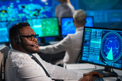 Workplace of the air traffic controllers in the control tower. Diverse team of aircraft control officers works using radar, computer navigation and digital maps. Aviation concept.