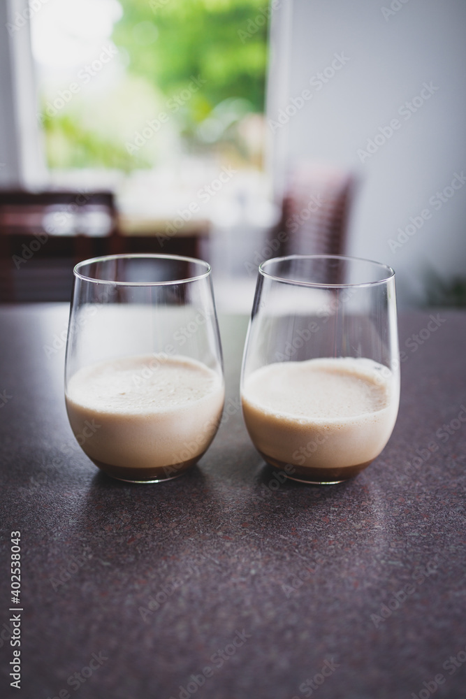 couple of espresso martinis in wine glasses on kitchen counter with dining room bokeh couple of espresso martinis in wine glasses on kitchen counter with dining room bokeh