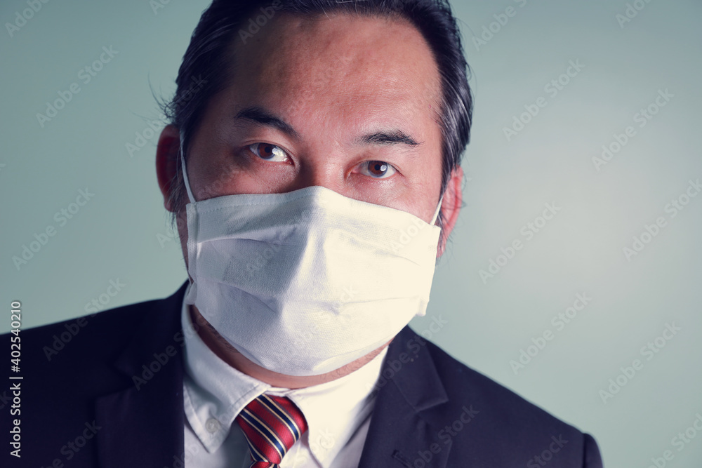 Close up portrait of adult Asian businessman wearing a medical mask looking at camera. Close up portrait of adult Asian businessman wearing a medical mask looking at camera.