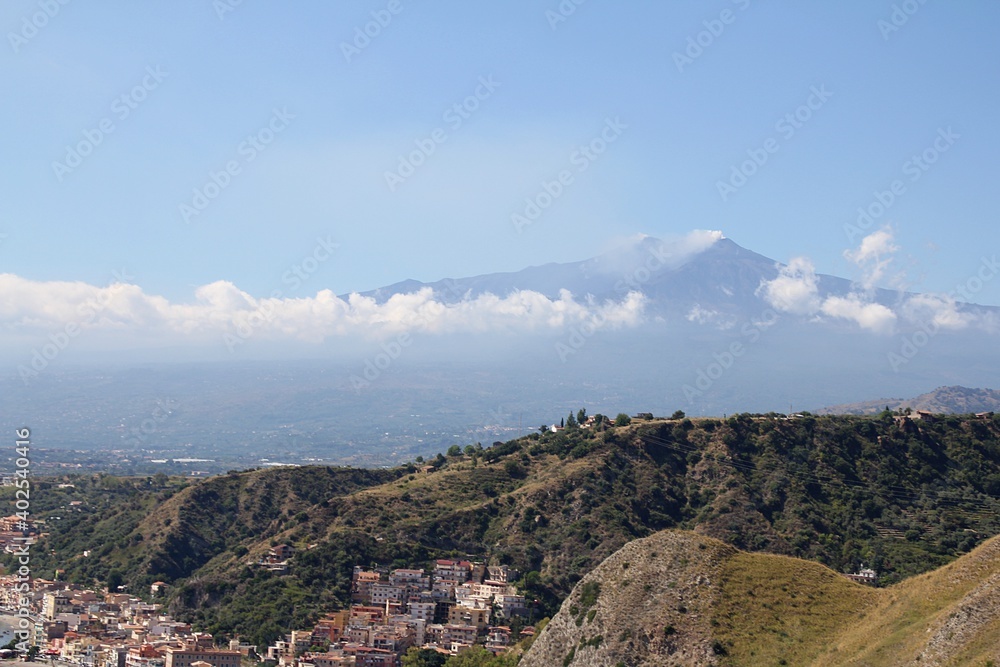view of Mount Etna, the hills, the mountains in front of the volcano and the town by the sea