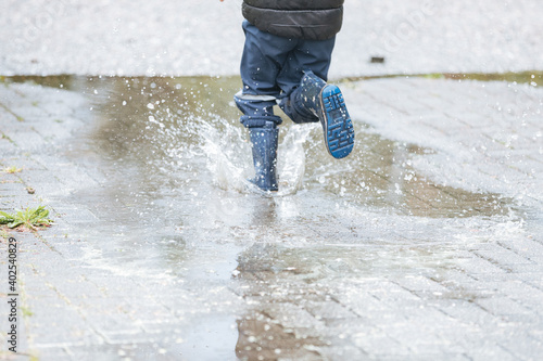 Child with rain boots jumps in puddles