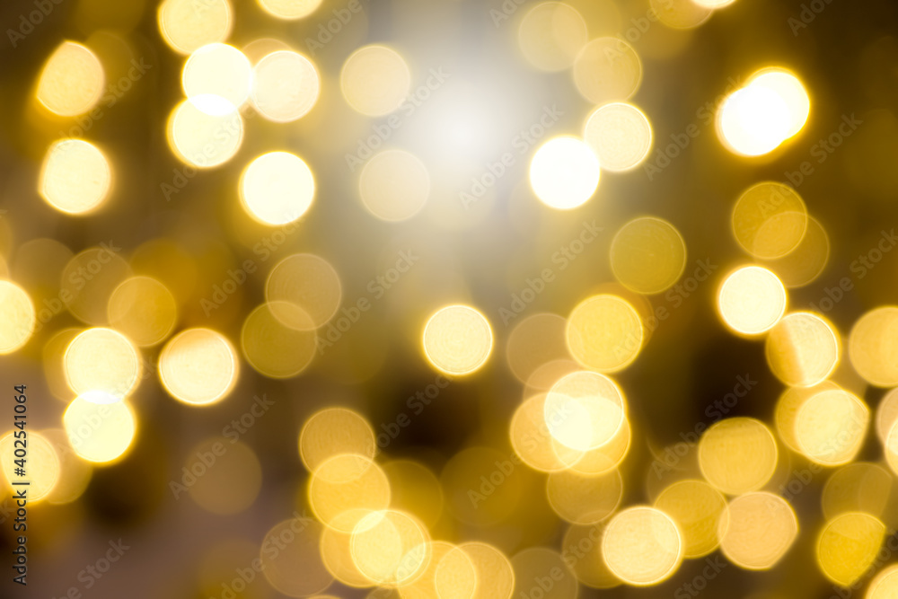 Golden yellow light glowing background in the form of bokeh. Shimmering blur spotlights on multicolored abstract wallpaper.