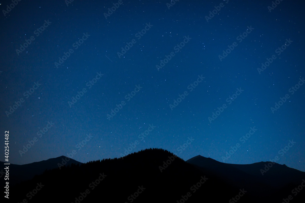 Silhouette of mountain range under dark blue night sky with many bright stars Silhouette of mountain range under dark blue night sky with many bright stars