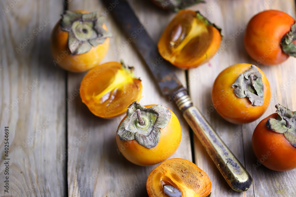 Fototapeta premium Fresh persimmon on a wooden surface. Persimmon halves. Winter fruit.