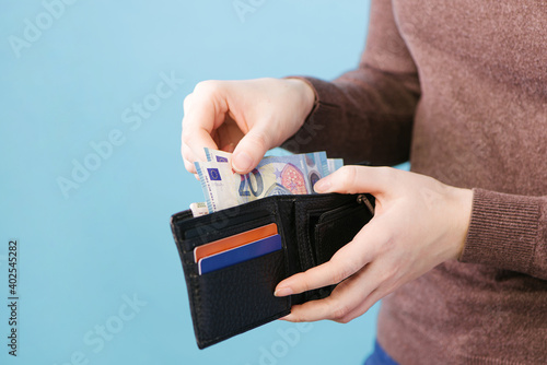 Foto A woman takes out money from a wallet on a blue background with a place for text