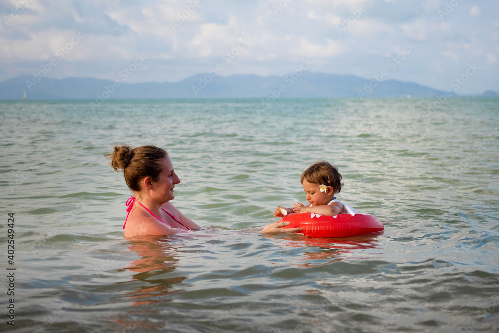 Cheerful girl swimming with her mom at sea.