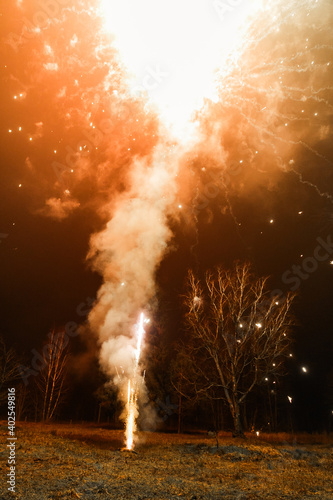 Bright colorful New Year's fireworks in the field in the village. Multi-colored fireworks lights. Flash in the village. Belarus. December 2020.