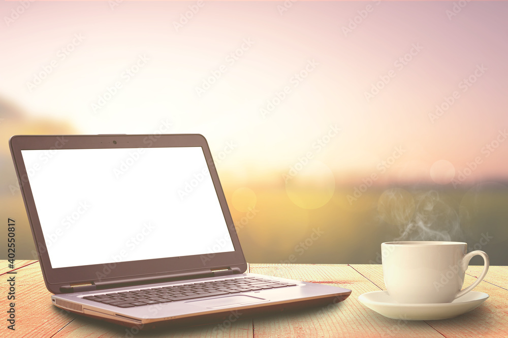 Fototapeta premium laptop and a cup of coffee on wooden table and sunrise nature background