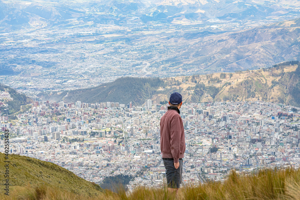 Men from behind intentionally blurred contemplating the city of Quito, Ecuador, from above.