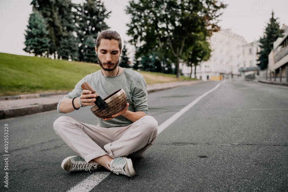 Fototapeta premium man holding and playing a singing bowl tibetan bowl