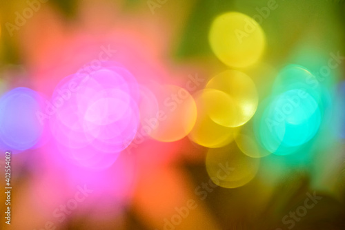 Multicolored holiday lights in defocus. Blurred abstract illuminate decorative lights with bokeh in night background.