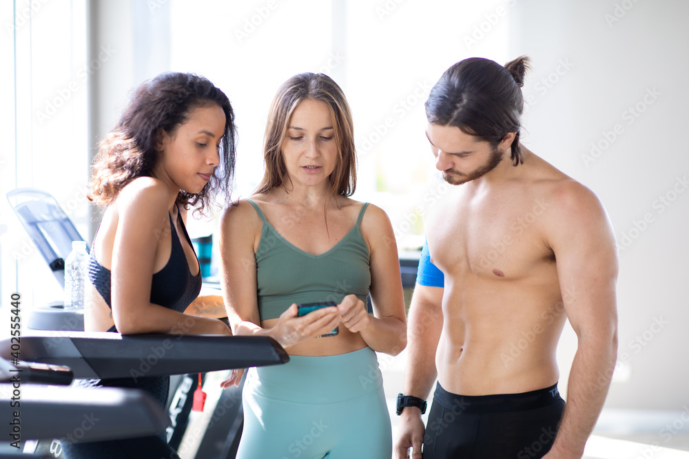 Fototapeta premium Group portrait of diverse young sporty talking and laughing together after a workout at gym. Fitness and healthy lifestyle concept.