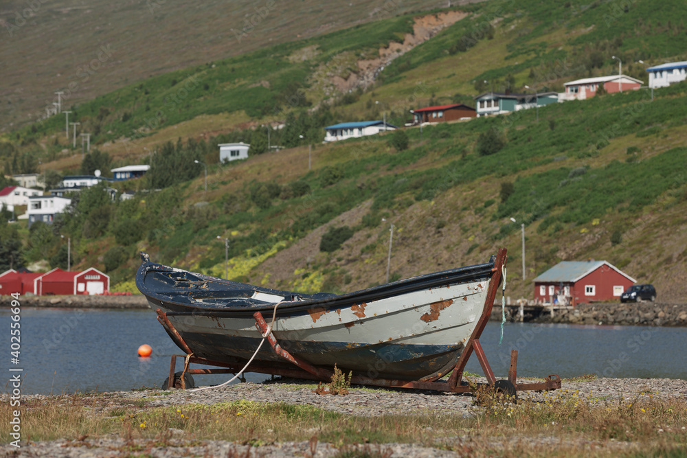 Old vintage boat with a small town of Eskifjodur located in east Iceland in the background